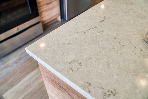 A countertop with a wooden edge and a stainless steel refrigerator in the background.