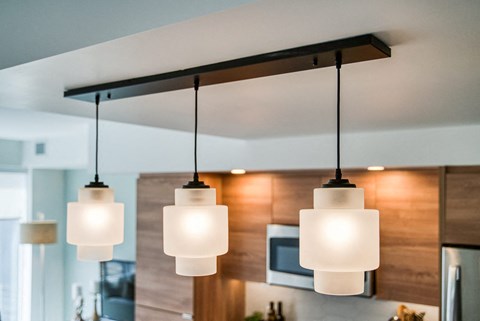 Three hanging lights are on in a modern kitchen.