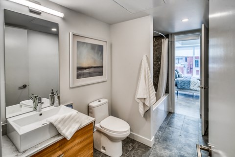 A bathroom with a toilet, sink, and a painting on the wall.