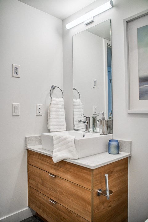 A bathroom with a sink, mirror, and towel rack.
