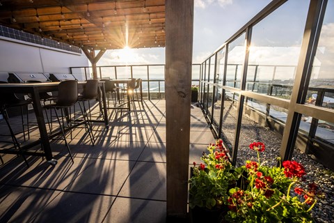 A sunny day at a rooftop patio with tables and chairs.