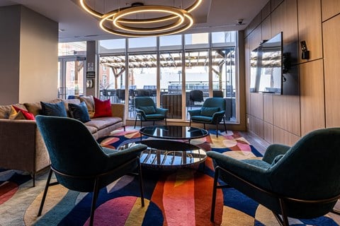 A modern living room with a large window and a colorful rug.