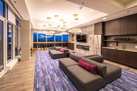 A modern living room with a grey couch and a purple rug.