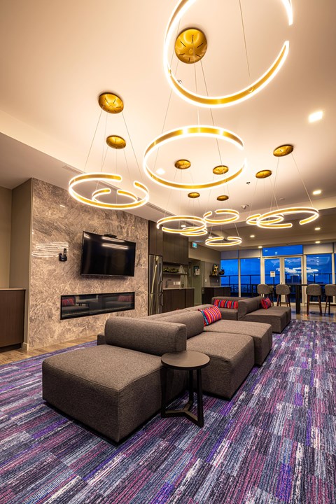 A modern living room with grey sofas and a purple carpet.