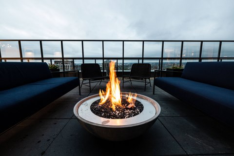 A fire pit with flames in the middle of a patio.