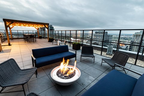 A patio with a fire pit and chairs.