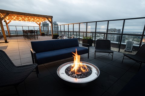 A fire pit sits in the middle of a patio with a couch and chairs around it.