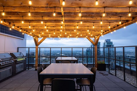 A wooden pergola with string lights above a dining table with chairs.