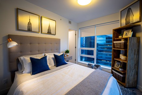 A bedroom with a large bed and a wooden bookshelf.