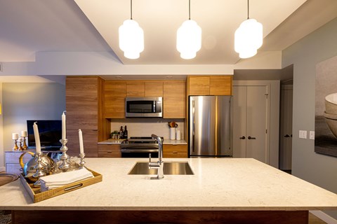 A modern kitchen with a marble countertop and stainless steel appliances.