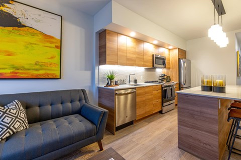 A modern kitchen with a grey sofa and a painting on the wall.