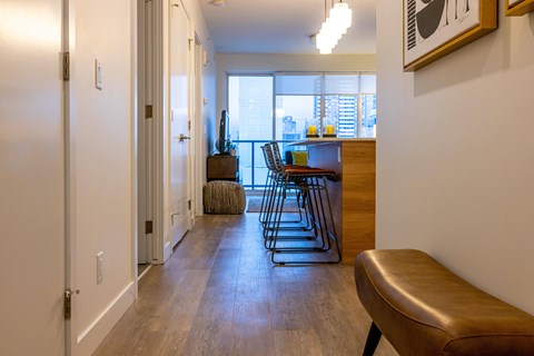 A long hallway with a brown bench and a chair.