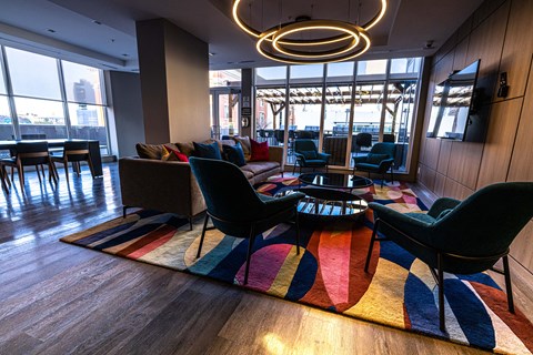 A modern living room with a large rug and a circular light fixture.