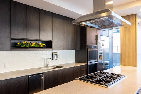 A modern kitchen with dark wood cabinets and a stainless steel range hood.