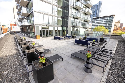 A modern outdoor seating area with black planters and benches.