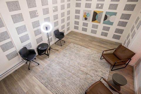 A room with a grey carpet and a white wall with a painting on it.