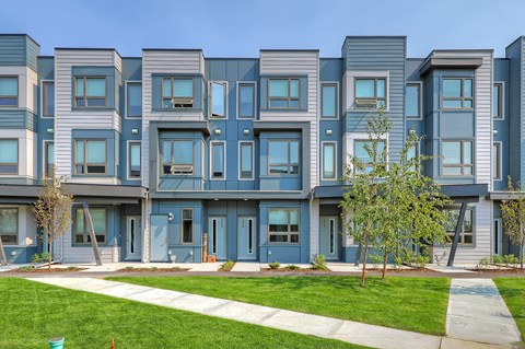 A row of modern townhouses with blue doors and windows.