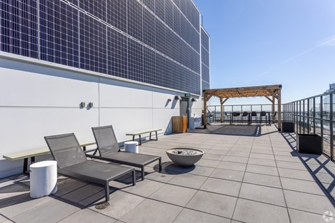 A rooftop patio with a bowl, chairs, and a table.