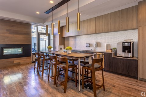 A modern kitchen with wooden chairs and a long table.