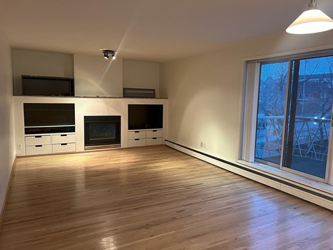 A room with wooden floors and a window showing a view of a building outside.