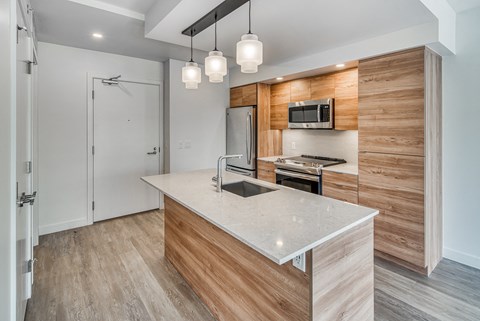 A modern kitchen with a wooden accent wall and a white island.