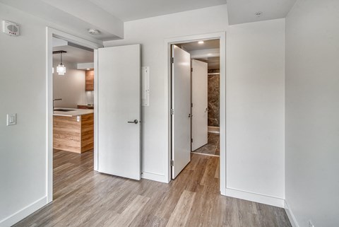 A white interior with a wooden floor and two white doors.