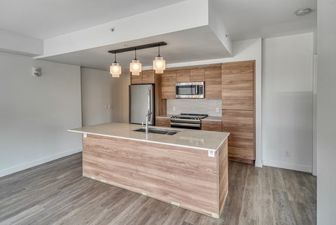 A modern kitchen with a wooden island and a flat screen TV mounted above it.