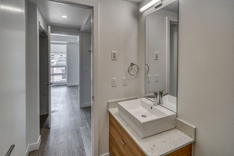 A bathroom with a sink, mirror, and a doorway leading to another room.