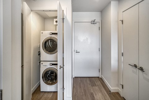 A white door is open to a hallway with a washing machine in the background.