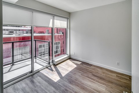 A room with a view of a red building through large windows.
