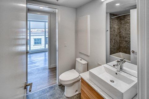 A bathroom with a toilet, sink, and mirror.