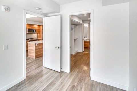 A white door is open to a room with a wooden floor.