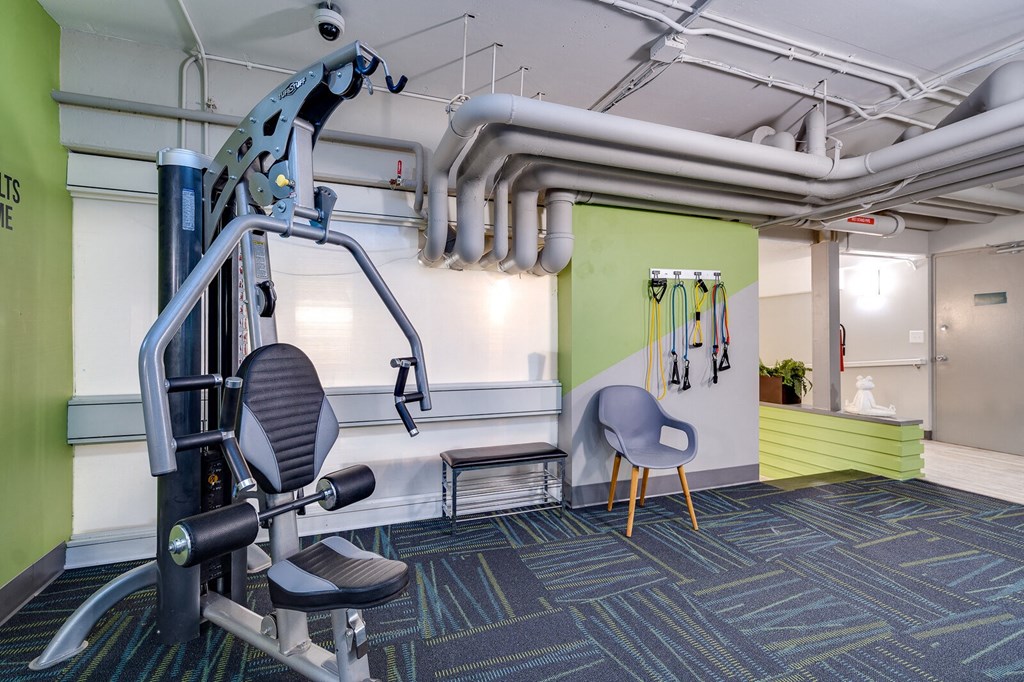 A gym room with a weight machine and a bench at Dayton, OH apartments.