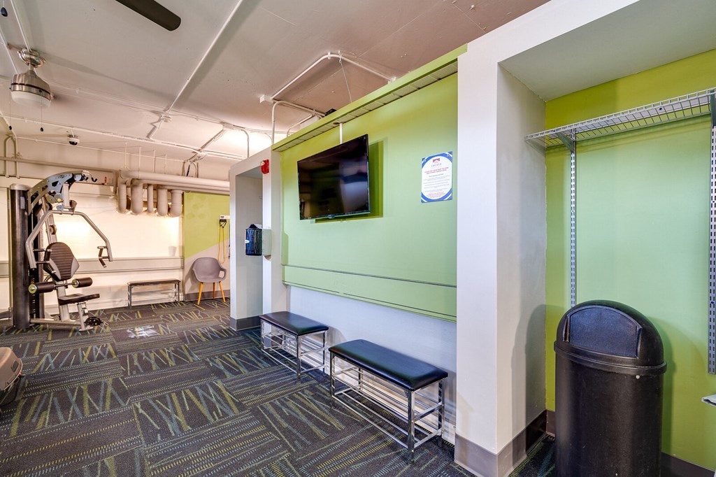 Resident fitness center at The View at Dayton Towers with a mounted television above two benches.