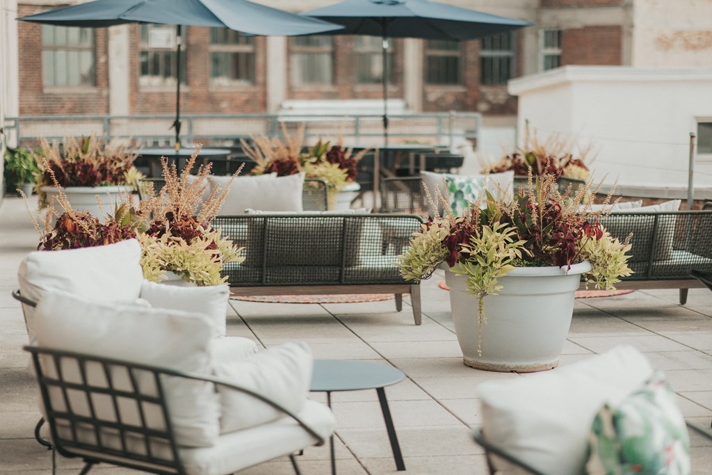 Rooftop patio seating area with umbrella seating, cushioned chairs, and potted plants at Dayton, OH apartments.
