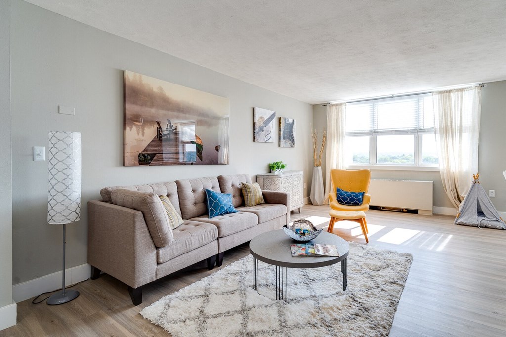 The View at Dayton Towers living room with large window, hardwood-style flooring, and a radiator.