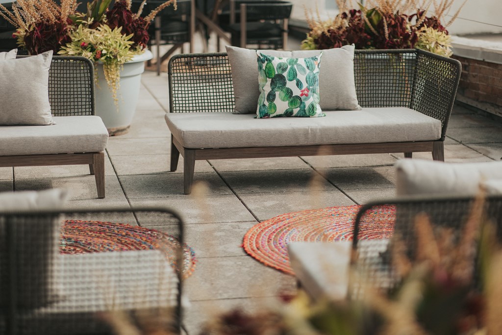 Rooftop patio with cushioned seating, rugs on tile flooring, and potted plants at Dayton, OH apartments