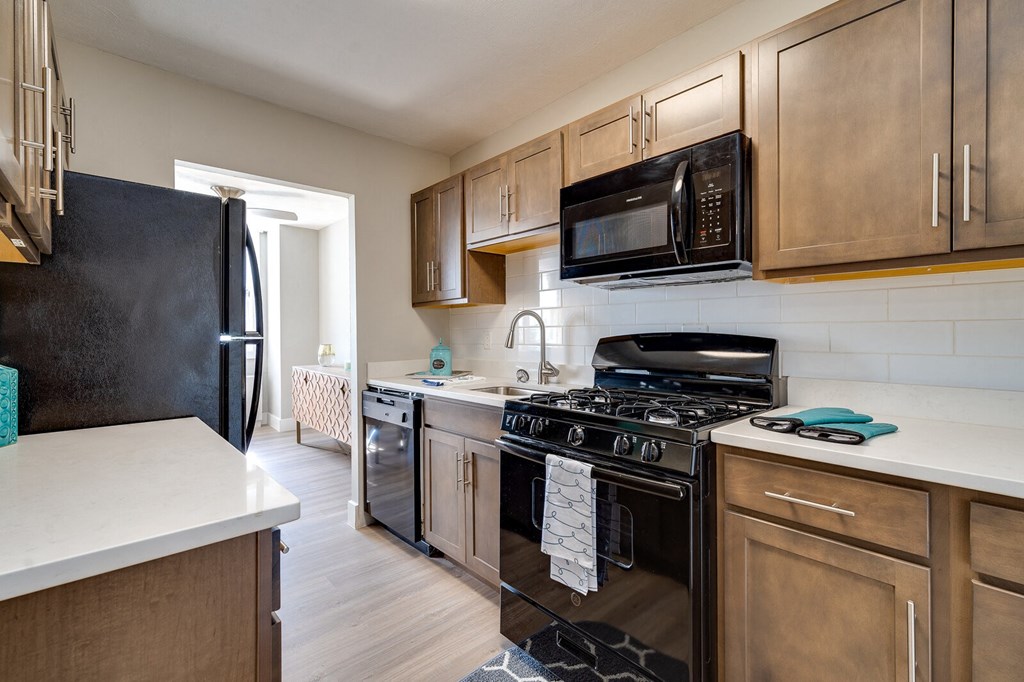 A kitchen with black appliances and wooden cabinets at The View at Dayton Towers Apartments in Dayton, OH.