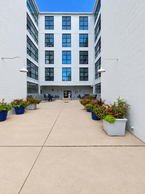 A courtyard with a white building and potted plants.