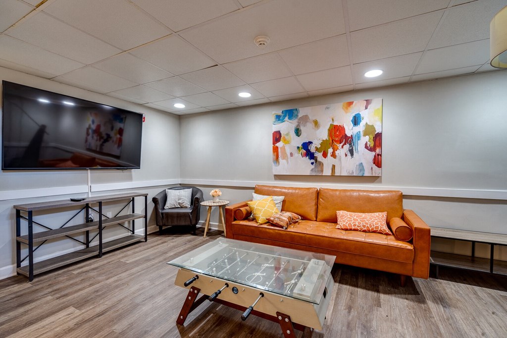 Dayton Towers resident clubhouse with large mounted television, small foosball coffee table, and seating area.