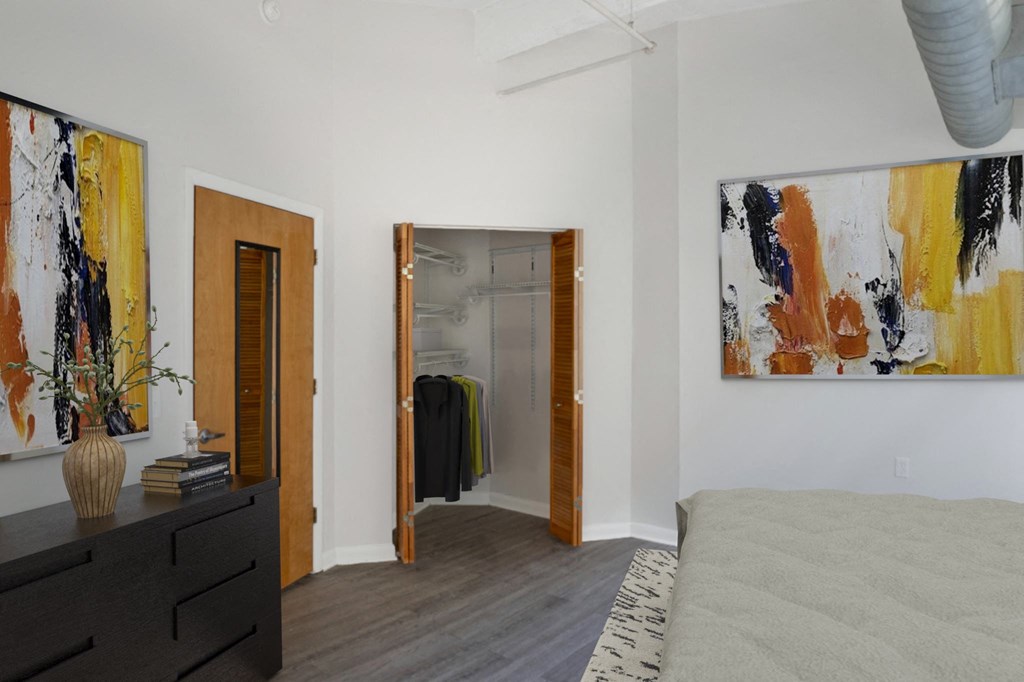 Apartment bedroom with a bed and paintings on the wall and hardwood-style flooring