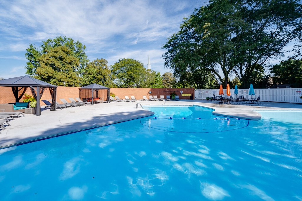 Dayton Towers resident swimming pool surrounded by trees and a white fence.
