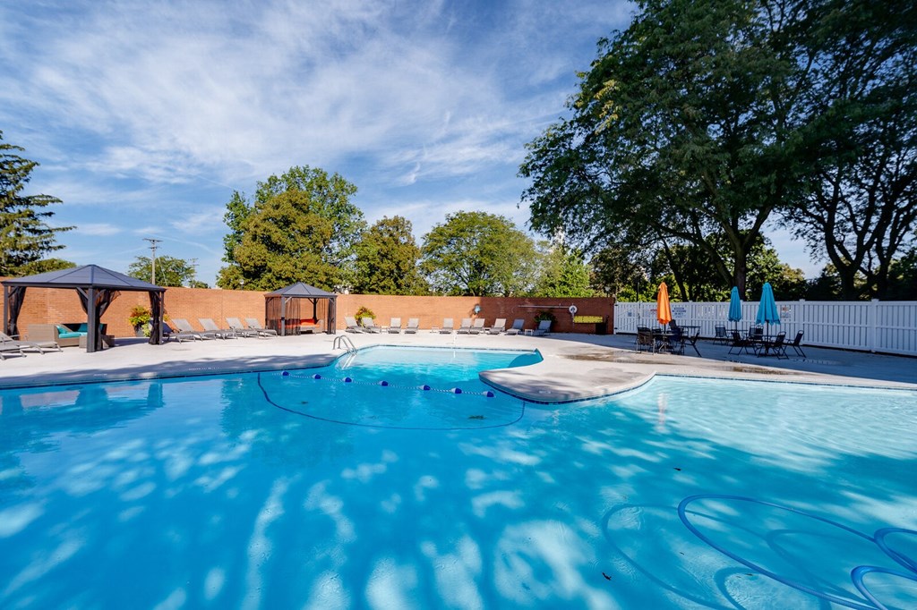 A large outdoor swimming pool with sun loungers and trees in the background at The View Dayton Towers Apartments