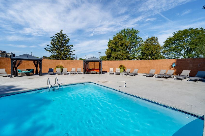 our swimming pool is next to a brick wall with chairs and a blue pool