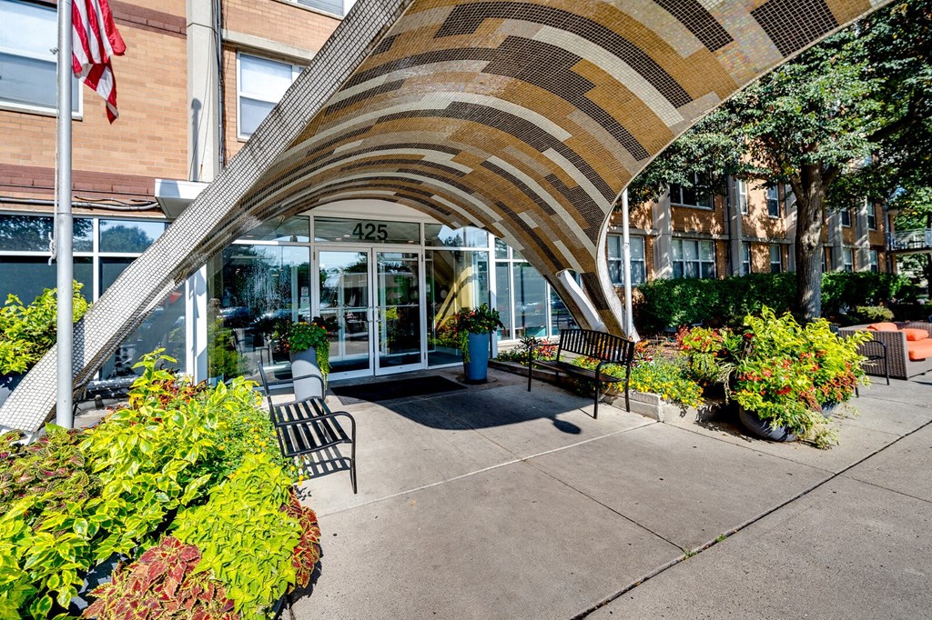 Entrance to The View at Dayton Towers with a curved roof and a person sitting on a bench.