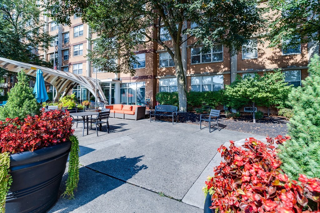 Apartment courtyard with a bench, seating areas, and a tree at Dayton Towers apartments.