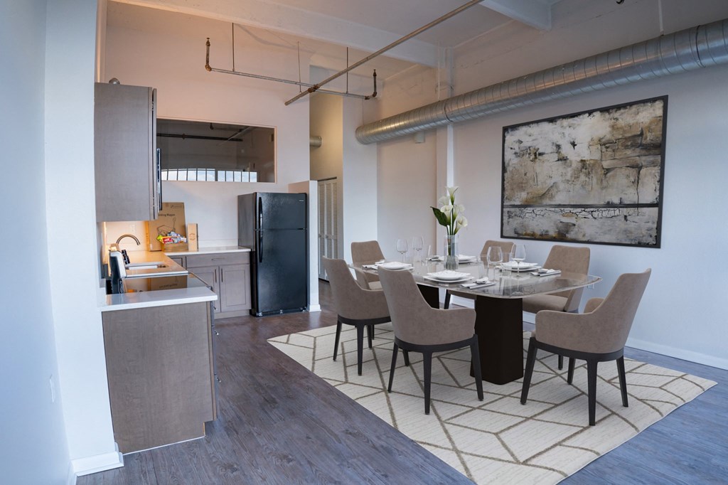 Apartment kitchen and dining area with hardwood-style flooring, open kitchen space, and central air.