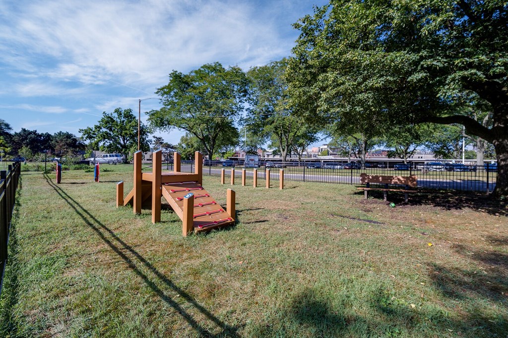 Dog park with obstacles such as weave poles and ramp made out of wood for Dayton Towers residents