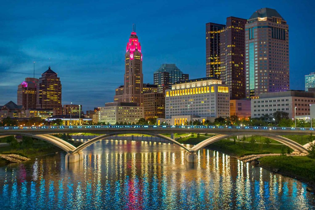 a city skyline at night with a bridge and a river