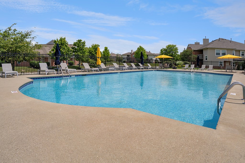 A large swimming pool surrounded by lounge chairs and umbrellas.